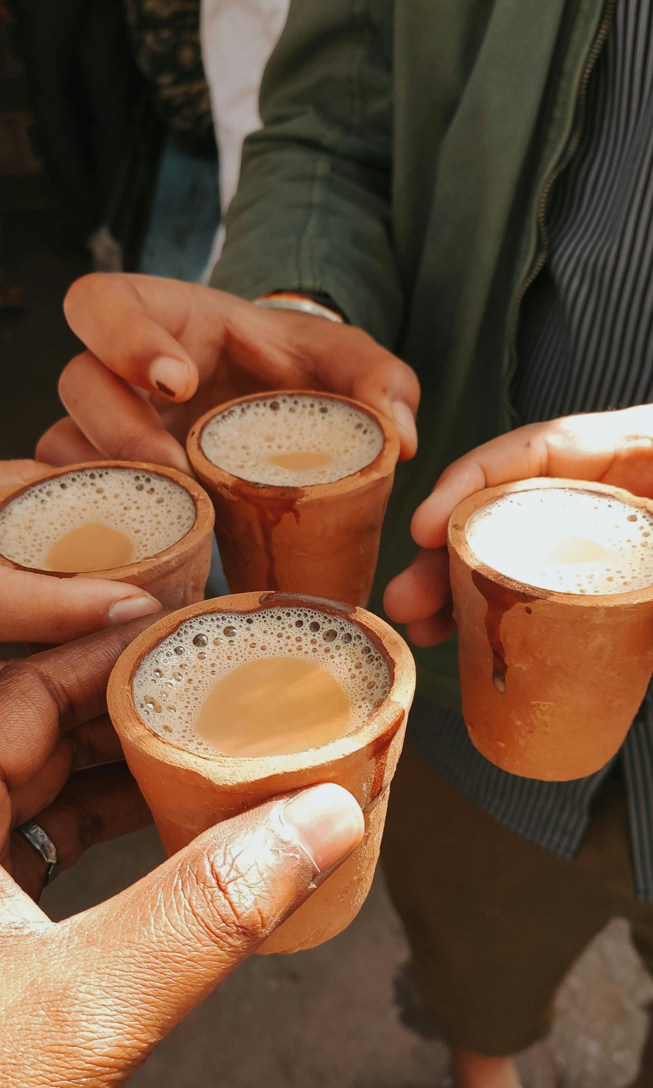 Friends toasting with traditional masala chai in clay cups, capturing a vibrant cultural moment.